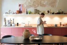 05 a bold pink kitchen with lower cabinets, a terrazzo countertop, a long shelf with decor and some built-in lights