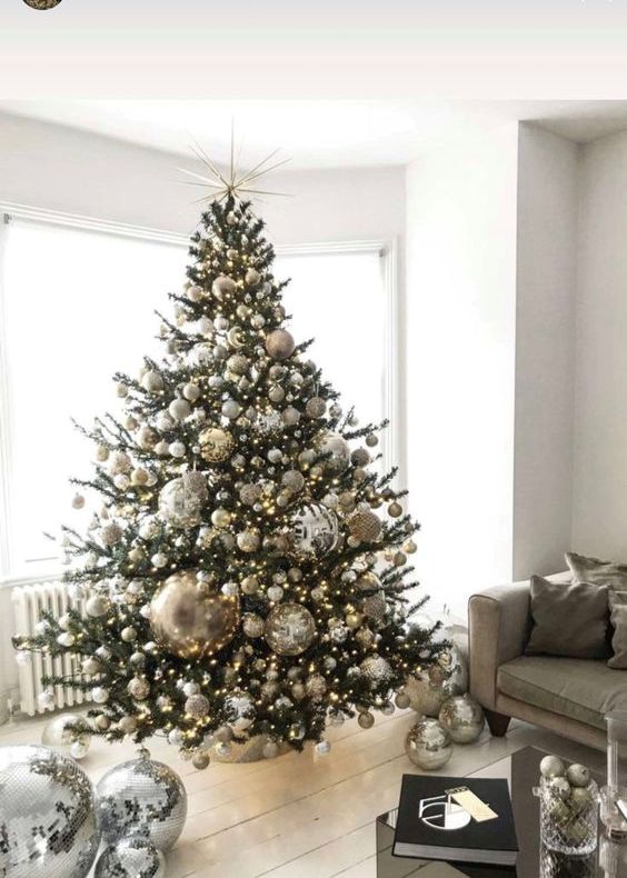 an unusual Christmas tree styled with silver and gold ornaments, disco balls on the tree and on the floor