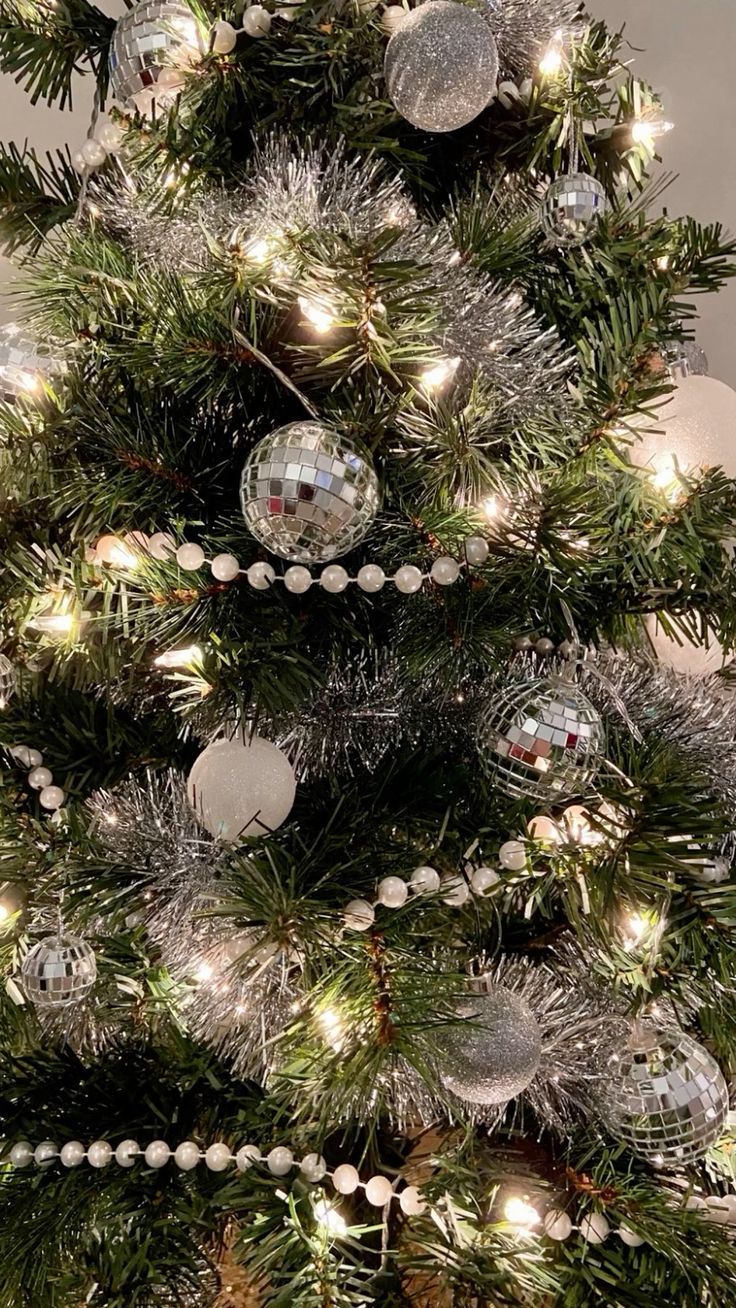 NYE Christmas tree decor with white, silver and disco ball ornaments, lights and bead garlands