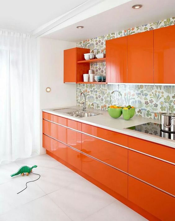 a bright and glossy orange kitchen with a floral backsplash and white countertops is a cool and juicy-colored solution
