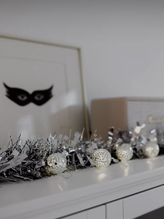 a NYE mantel with silver tinsel and a silver disco ball garland is awesome for a party and can be made fast