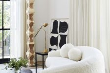 14 a chic contemporary living room with a creamy boucle sofa, a black table and some art, neutral drapes