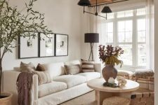 15 a light-filled earthy living room with wooden beams, a white sofa, stools and a woven chair, a grey side table and a round coffee table