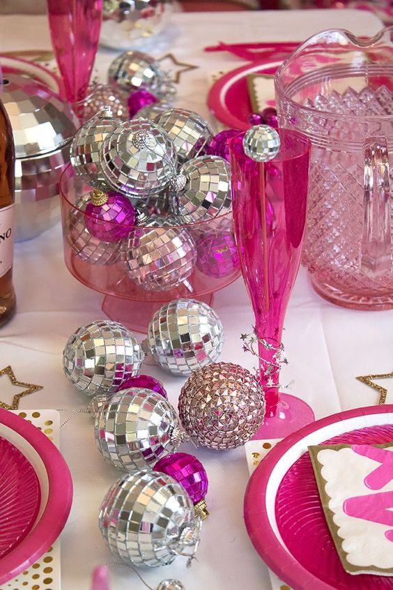 a bold pink and silver NYE party table with lots of disco balls is a cool and fun idea for the holiday parties