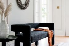 16 a lovely and pretty black boucle loveseat, a dried leaf wreath, a black side table for a chic and lovely space