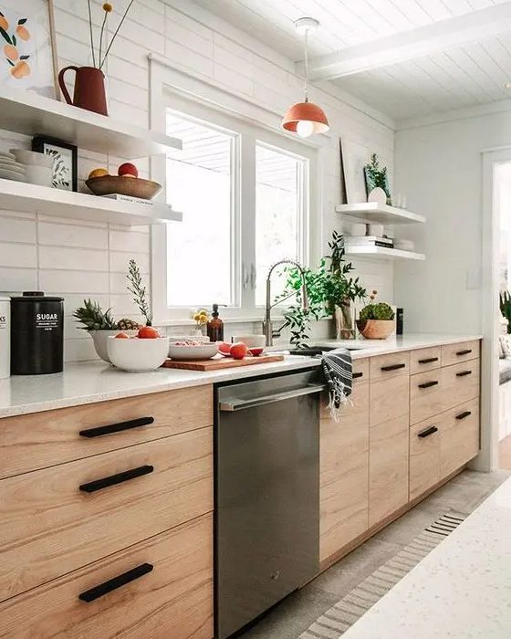 A mid century modern blonde wood kitchen with open shelves, black handles and a skinny tile backsplash