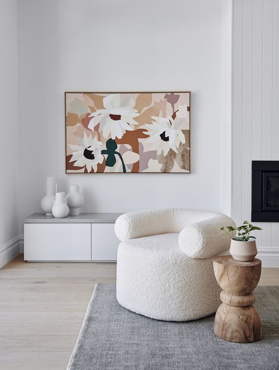 a pretty neutral living room with a creamy boucle sofa, a wood side table, a muted color artwork