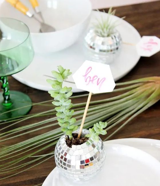 a disco ball planter with succulents and a place card will be a nice solution for a wedding or party tablescape