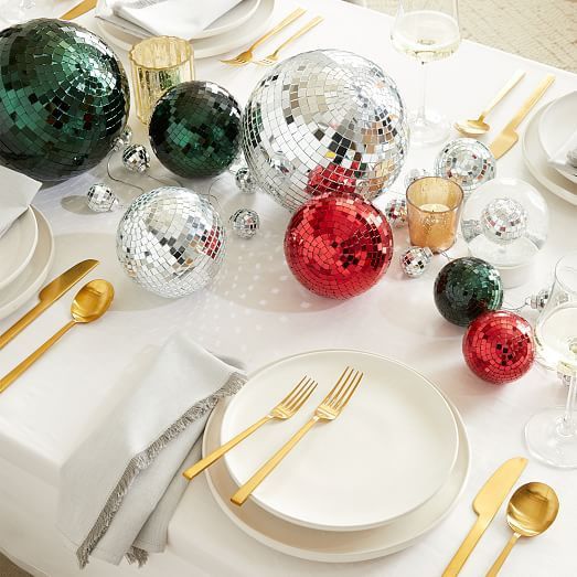 a neutral holiday tablescape with silver, red and dark green disco balls as a table centerpiece is awesome