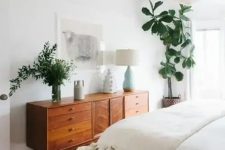 24 a mid-century modern stained dresser is used both for storage and for styling the space, it displays lamps and greenery