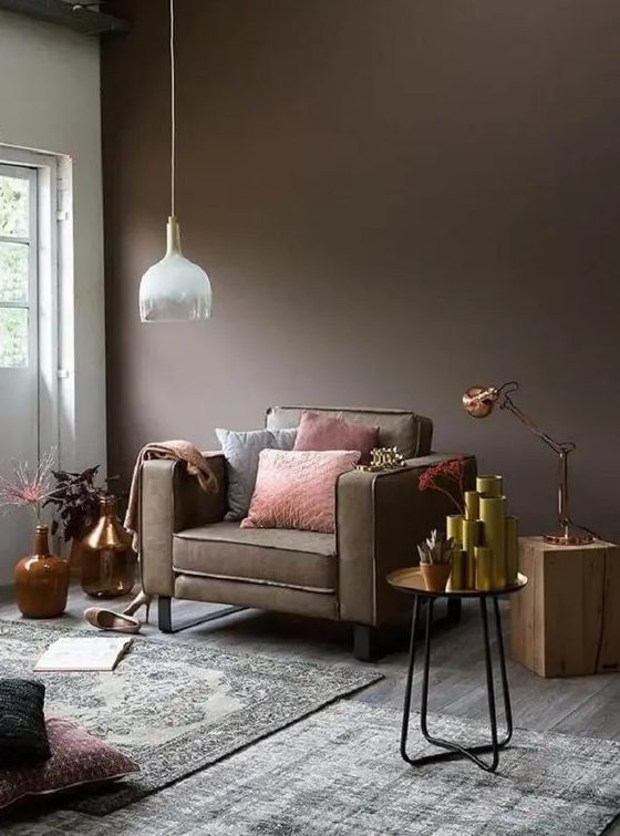 a taupe living room with a taupe chair, a tree stump and a metal side table, lots of vases, potted plants and layered rugs