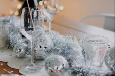 27 NYE party table styling with silver disco balls and tinsel is a cool and catchy decor idea for the holidays