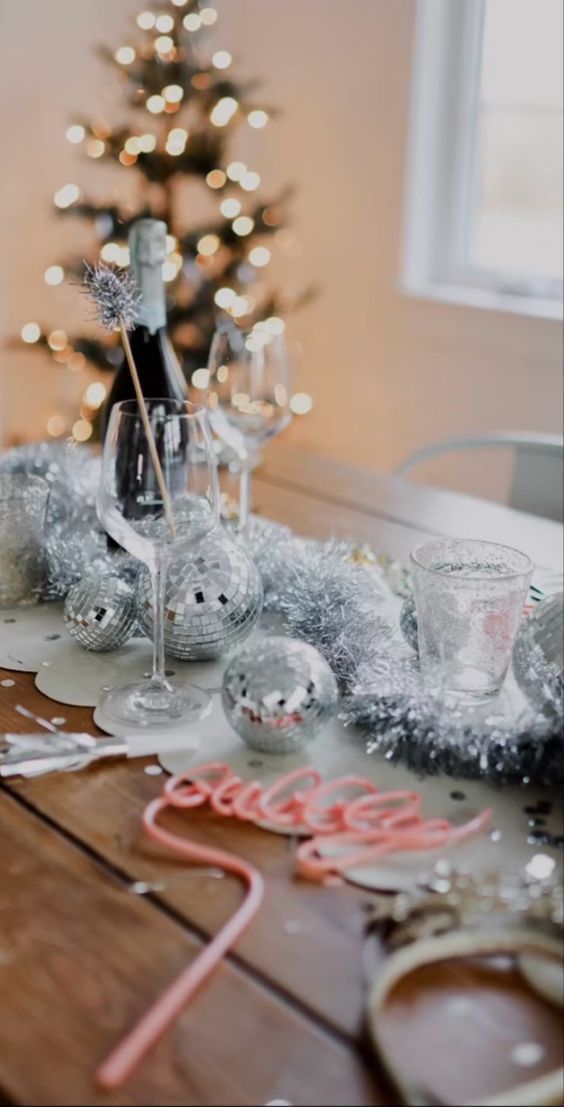 NYE party table styling with silver disco balls and tinsel is a cool and catchy decor idea for the holidays