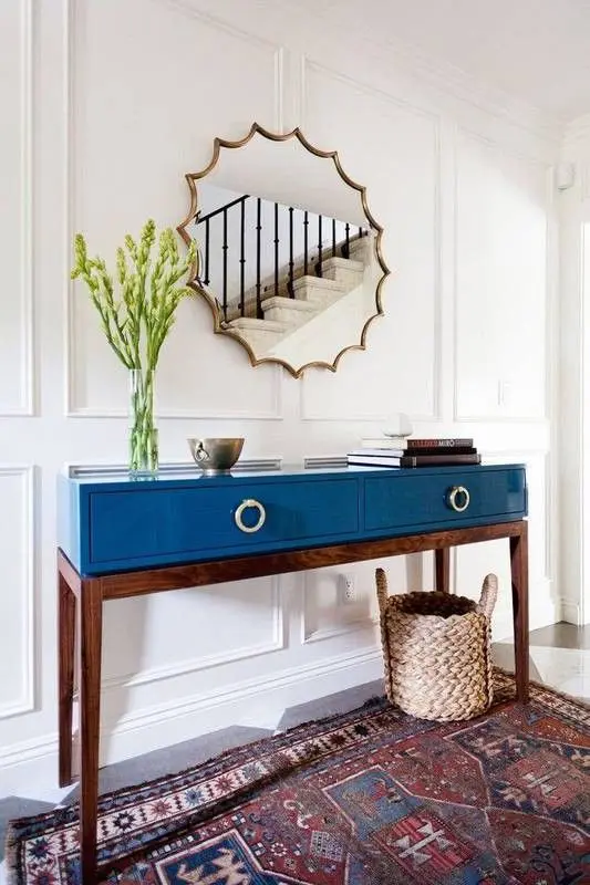 a lovely and bold blue lacquer console table on stained legs and with decor is amazing
