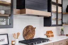 31 a stained wood kitchen with upper black glass cabinets, a black wood clad hood and white countertops