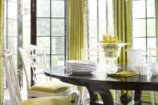 36 a bold eclectic dining room with chartreuse printed wallsa dn curtains, a dark table and yellow chairs plus a statement chandelier
