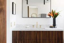 38 a dark-stained fluted vanity with a stone countertop, a mirror in a black frame, black pendant lamps and bold blooms