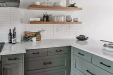 38 a light green farmhouse kitchen with black fixtures and white stone countertops and a white stacked tile backsplash