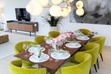 40 a modern dining room with a stained table, chartreuse chairs, a bubble chandelier and some art