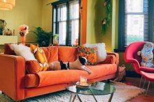 41 a colorful living room with chartreuse walls, an orange sofa and a pink chair, some plants and pendant lamps