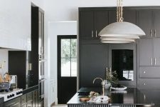 41 a modern black and white kitchen with black cabinetry, a white tile hood and a black fluted kitchen island with glossy countertops