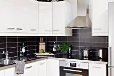 41 a modern contrasting kitchen with white cabinets, a black stacked tile backsplash and metal countertops is extra bold