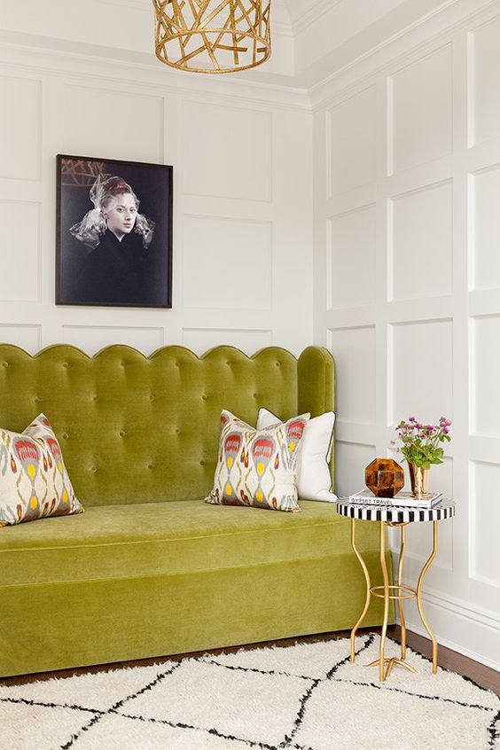 a beautiful English chic space with paneled walls, a chartreuse loveseat, a coffee table and printed pillows