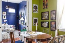 47 an eclectic dining room with chartreuse walls, a stained table, mismatching chairs, a crystal chandelier and a corner gallery wall