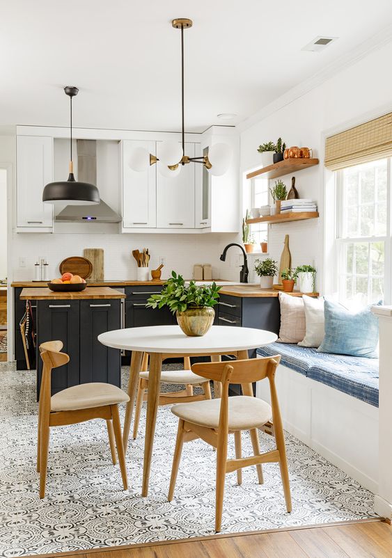 a contrasting two-tone kitchen with butcherblock countertops, open shelves, a windowsill bench and a table with chairs