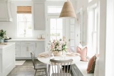 50 a white farmhouse kitchen with a large kitchen island and a dining zone that includes a windowsill bench