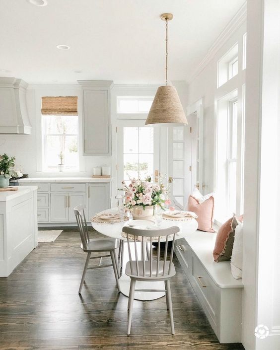 a white farmhouse kitchen with a large kitchen island and a dining zone that includes a windowsill bench