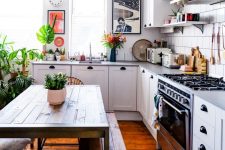 51 a cozy white farmhouse kitchen with neutral countertops, open shelves, a stained dining set with benches