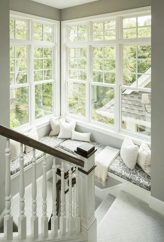 a corner window at the staircase with a large daybed with pillows and a blanket to enjoy a book and a cup of tea with a view