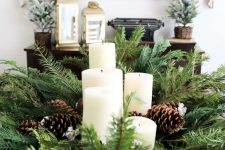 a Christmas bowl with evergreens, pillar candles and pinecones is a lovely rustic centerpiece for the holidays