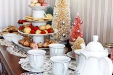 a Christmas tea party station with dolies, white printed porcelain, a tiered stand with cookies and sweets and bottle brush Christmas trees