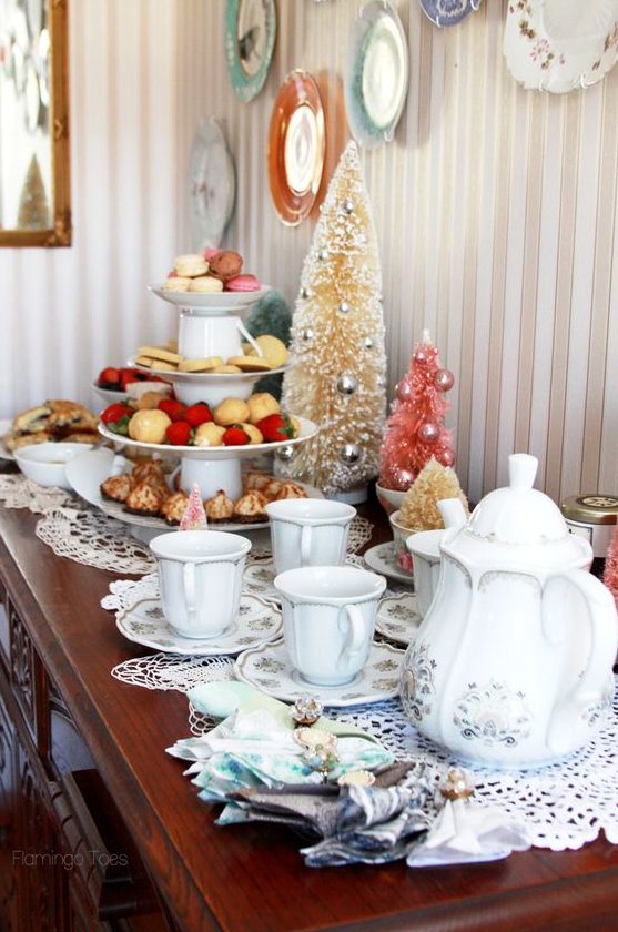 a Christmas tea party station with dolies, white printed porcelain, a tiered stand with cookies and sweets and bottle brush Christmas trees