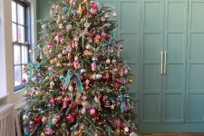a Christmas tree with lights, vintage ornaments, colorful bows, a star tree topper, colorful gifts under the tree