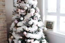 a Christmas tree with white faux fur, lights, white and pink ornaments, silver touches and chic round gift boxes under it