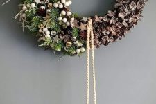 a beautiful Christmas wreath of evergreens and pinecones, wooden stars, white berries, a star with deer and hanging pinecones