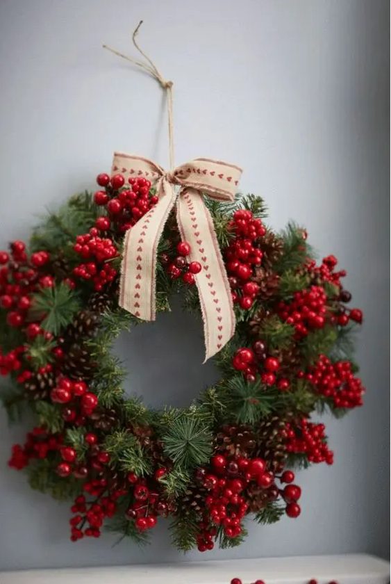 a beautiful Christmas wreath of evergreens, pinecones, cranberries and holly berries and a printed bow is amazing