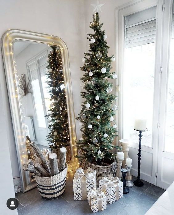 a beautiful slim Christmas tree with white and sheer ornaments and lights in a basket is a cool and catchy idea