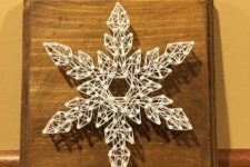 a beautiful snowflake Christmas string art piece in white is a delicate decoration to rock