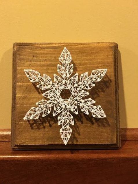 a beautiful snowflake Christmas string art piece in white is a delicate decoration to rock