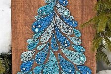 a blue string art piece showing a Christmas tree of drops, with pearls instead of ornaments is cool