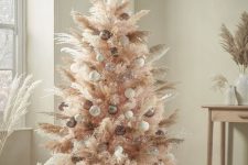 a blush boho Christmas tree decorated with white, taupe and clear ornaments and pampas grass