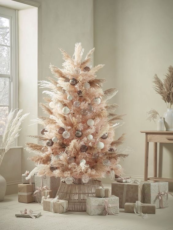 a blush boho Christmas tree decorated with white, taupe and clear ornaments and pampas grass