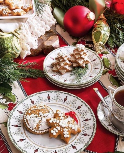 a bold Christmas tea party table with gingerbread cookies, printed porcelain, red textiles and evergreens