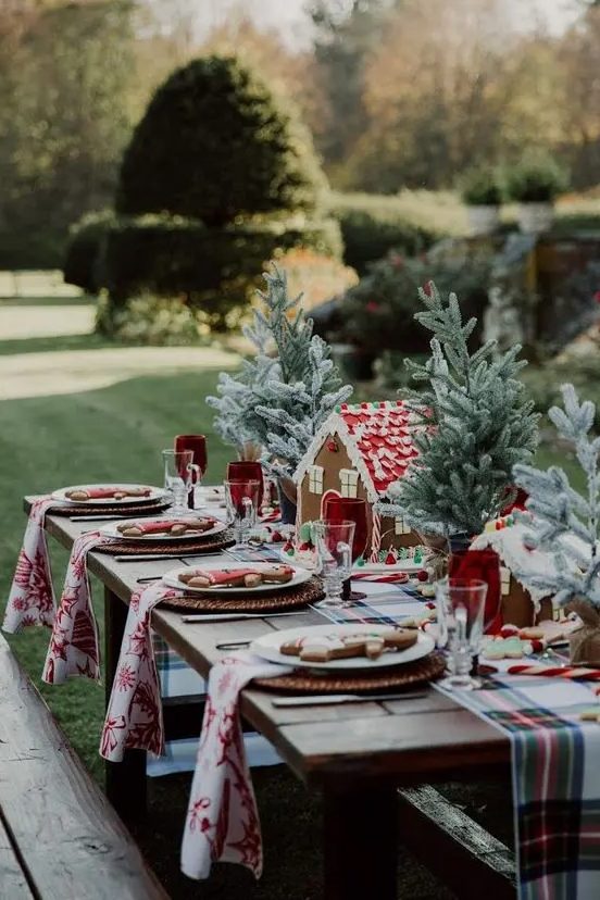 a bold and cool Christmas table setting with a plaid runner and printed napkins, tabletop Christmas trees, gingerbread houses and men