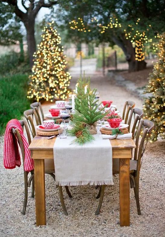 a bold and cool Christmas tablescape with a neutral runner, tree slice placemats, tabletop Christmas trees and red and white bowls