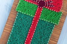 a bright Christmas string art piece showing a gift box, done in red and green, is a cool and catchy decor idea